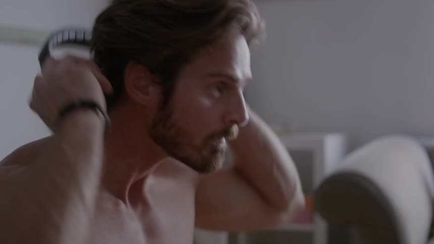 Shirtless man takes a breath and puts on headphones