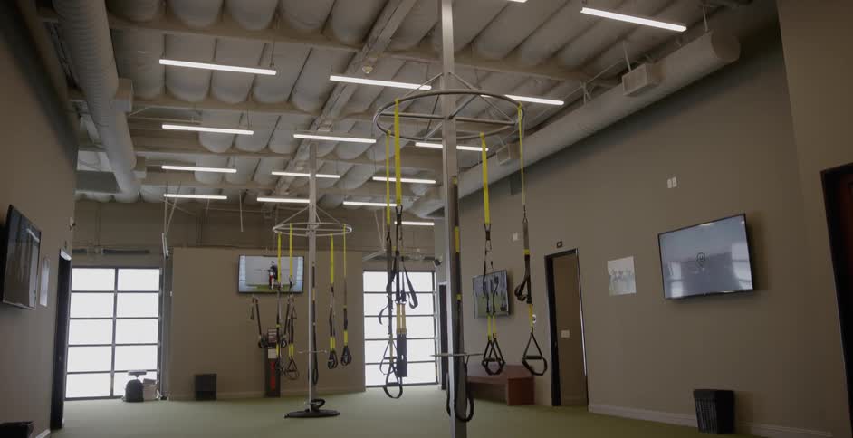 An empty gym with yellow resistance straps hanging from the ceiling