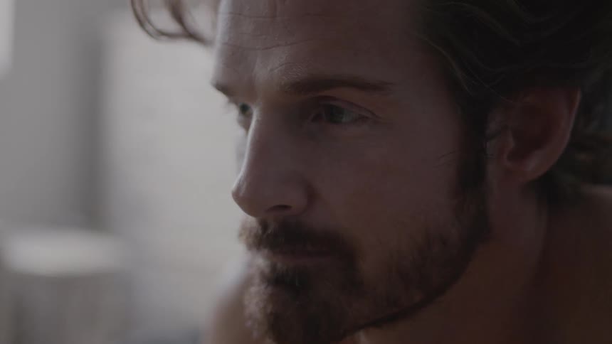 A shirtless man is deep in thought