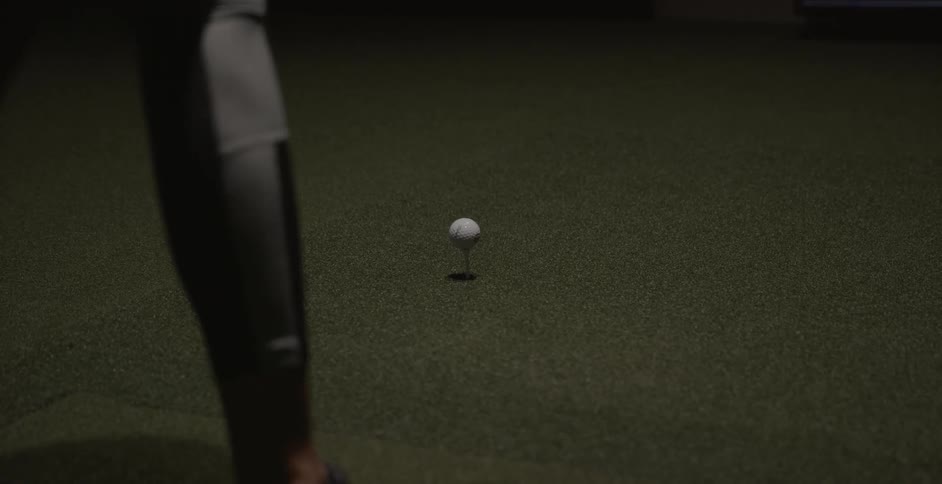 A woman is driving a golf ball of a tee