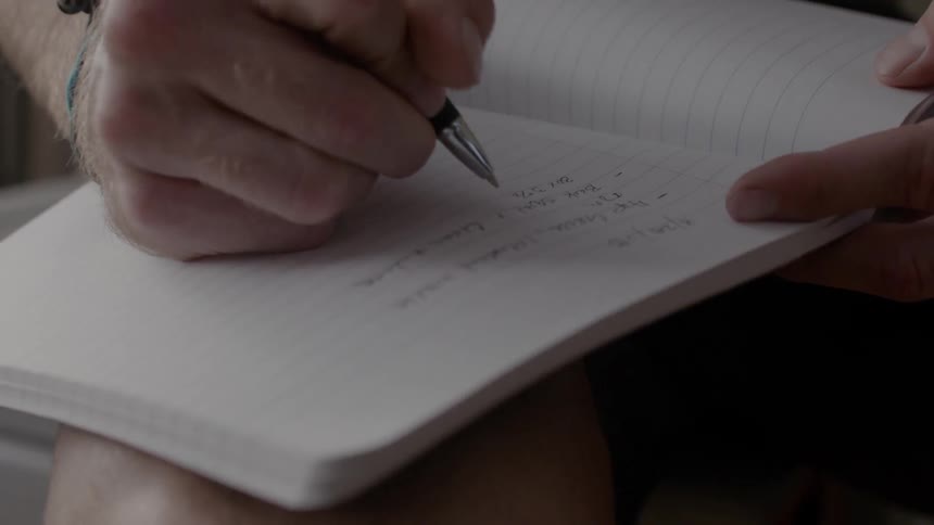 A man writes in a notebook
