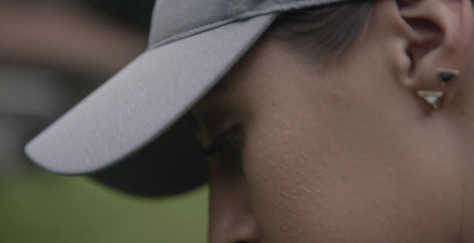A female golfer is wearing a cap as she stands outside during the day