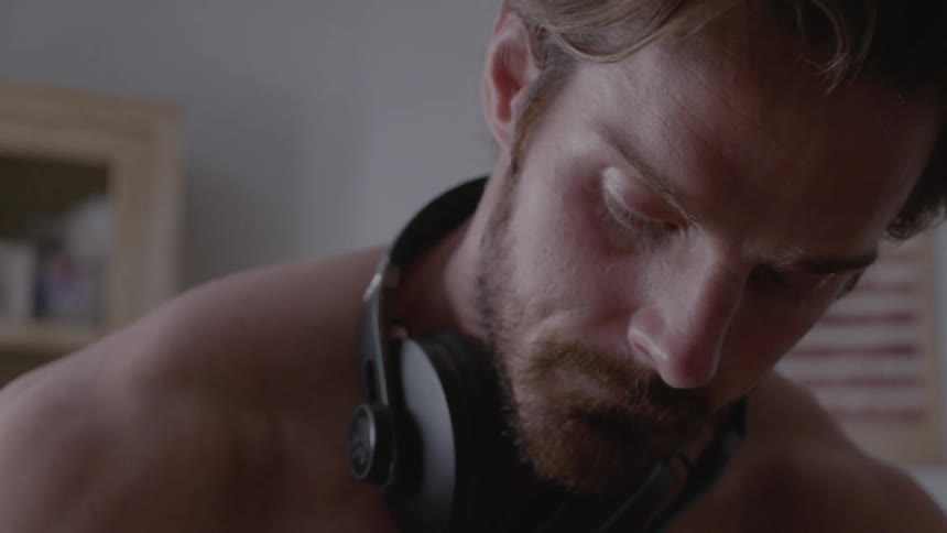 A man wearing headphones looks down at something