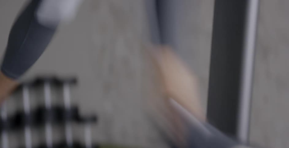 A woman is running on a treadmill in a gym during the day