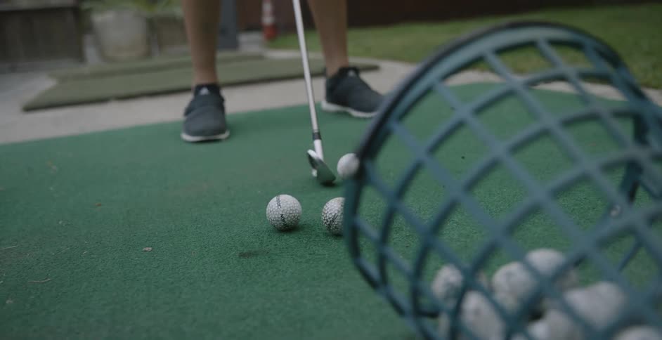 A female golfer is practicing on a driving range during the day