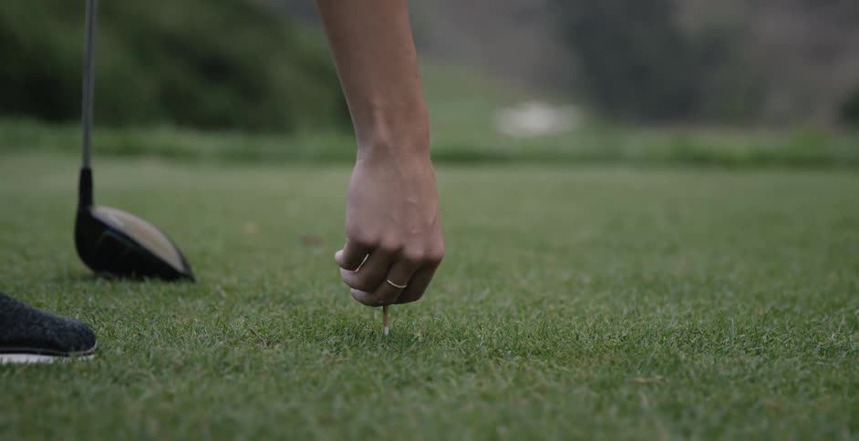 Someone is placing a golf ball on a tee