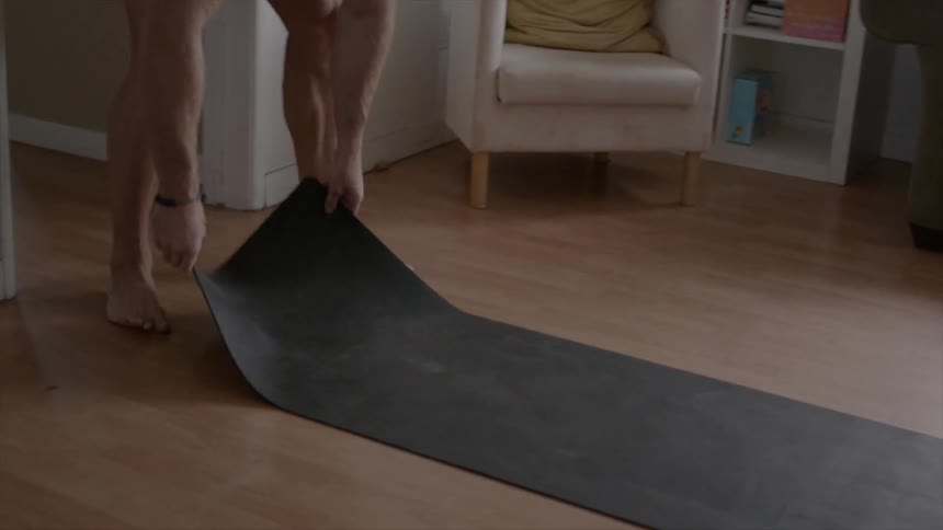 Someone is rolling a mat out onto the living room floor