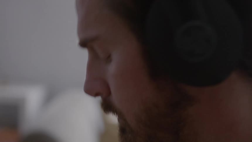 A guy is wearing headphones and looking at something off screen