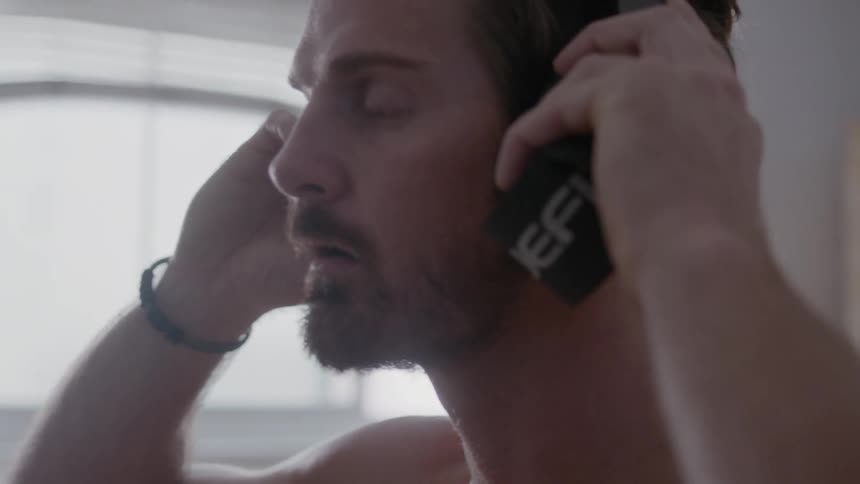 Man puts headphones on while sitting on couch