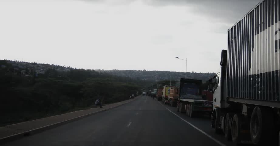 Trucks are stopping in a long line of traffic on a highway during the day