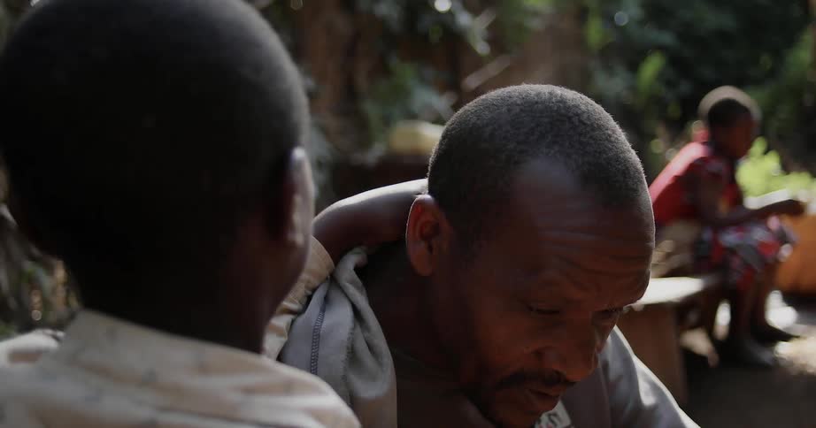 A young boy and his father are sitting and talking to each other