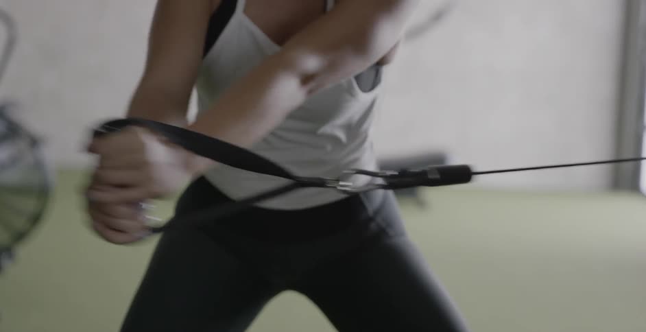 A woman is using a resistance machine in the gym
