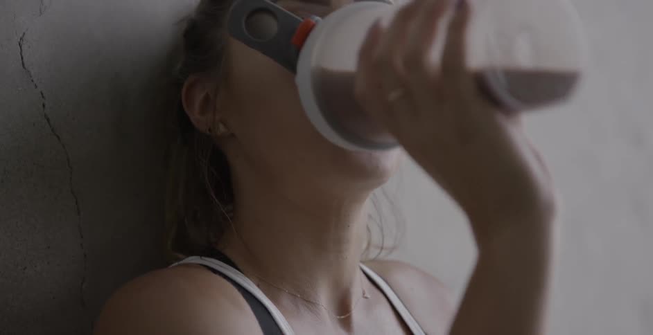A woman is taking a drink from a sports bottle