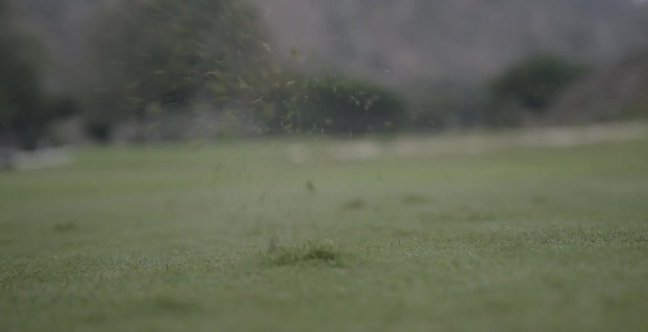 Someone is hitting a golf ball with a club
