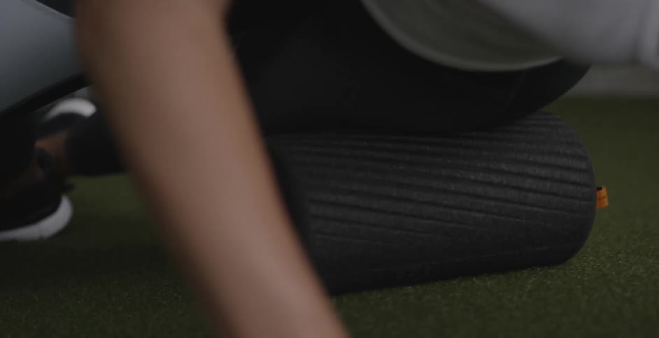 A person rolls their hip along the floor using an exercise roller