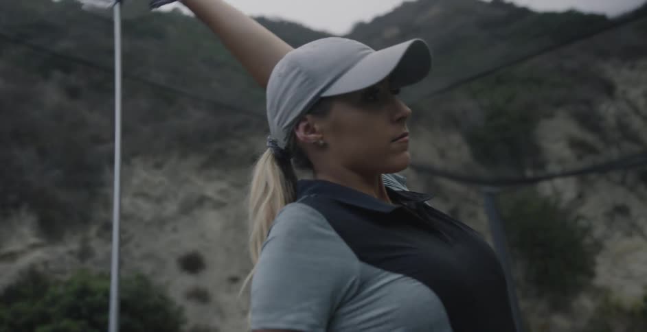 A woman is using a golf club to stretch