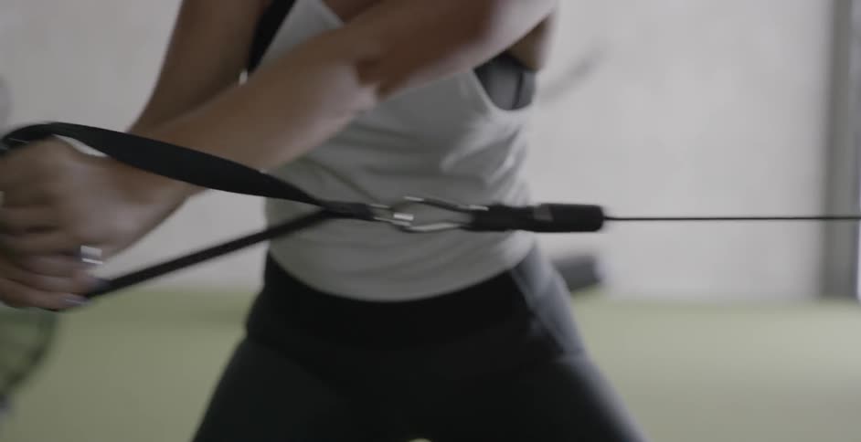 Woman pulls a cord on an exercise machine