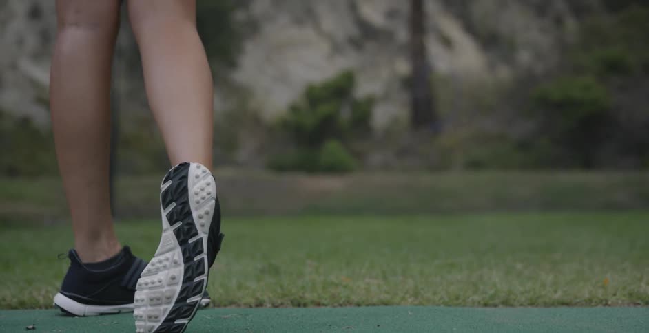 A woman golfs at a driving range
