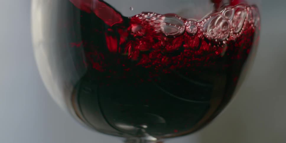 Red wine is poured into a wine glass
