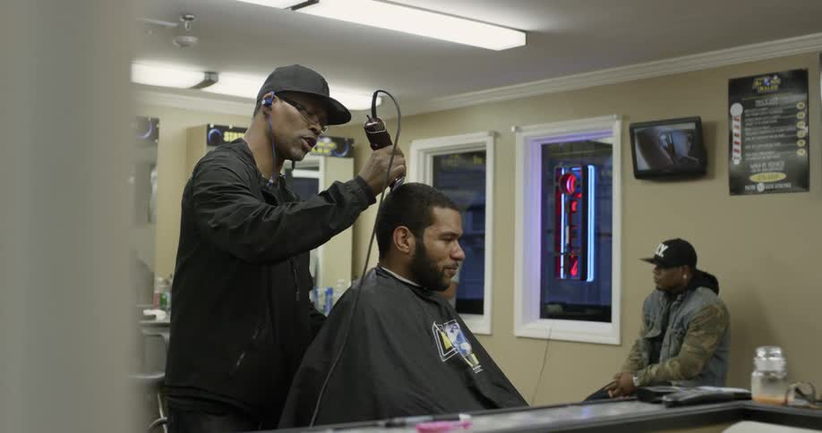 Man shaves another man's head in a barber shop