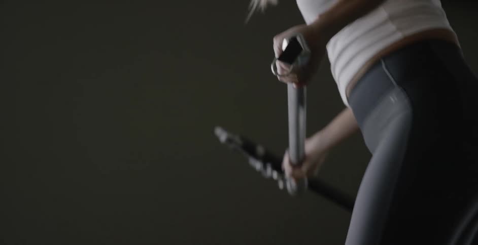 A woman swings a resistance bar downwards