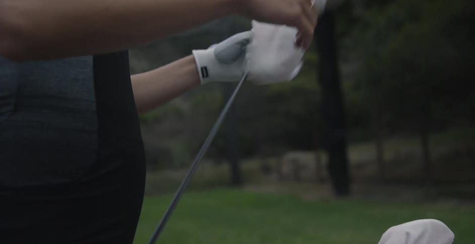 Woman wears glove as she grabs a golf club