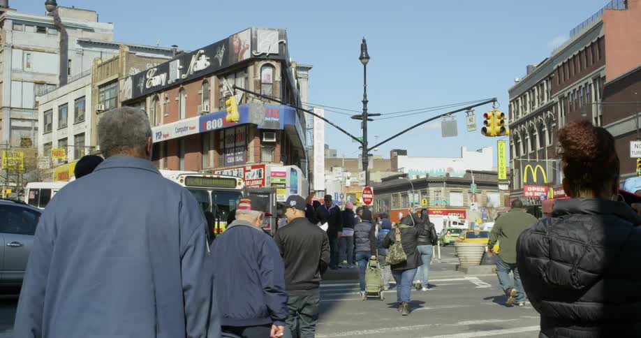 People are crossing a very busy intersection in the middle of a city