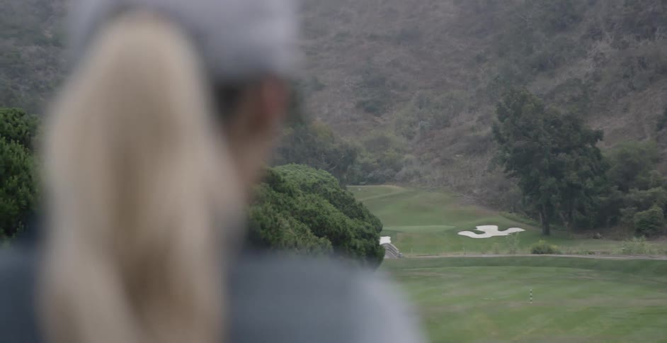A woman stands on a golf course
