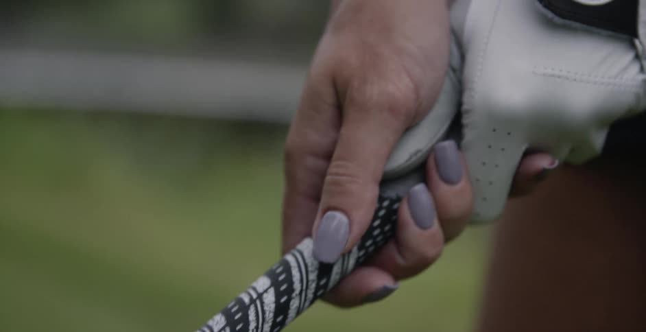 A woman is adjusting her grip on her golf club