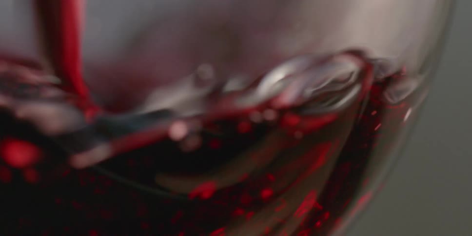 Red liquid is being poured into a glass