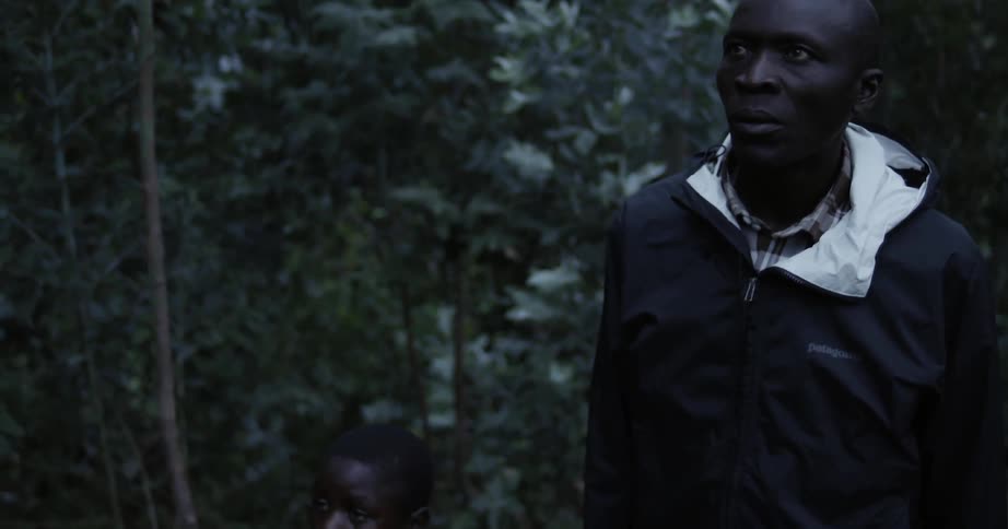A man is muttering as he stands in a natural setting at dusk