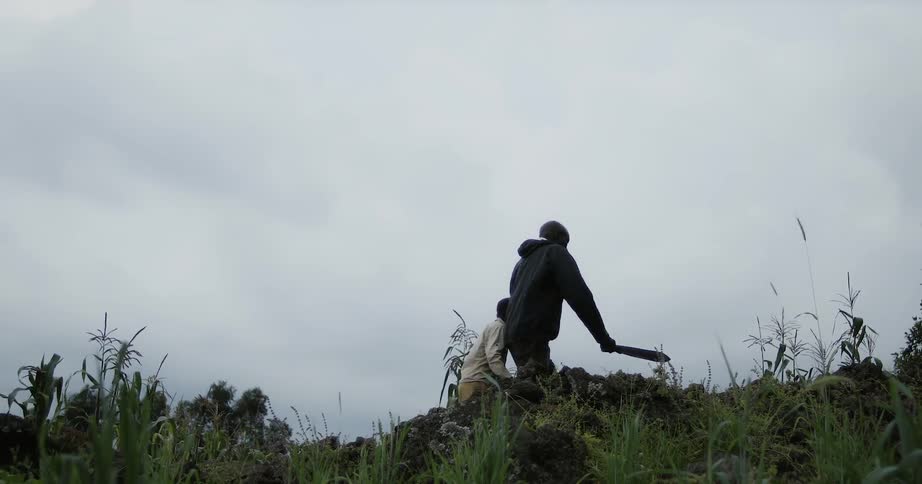 Man and boy hike across the top of a hill as clouds gather overhead