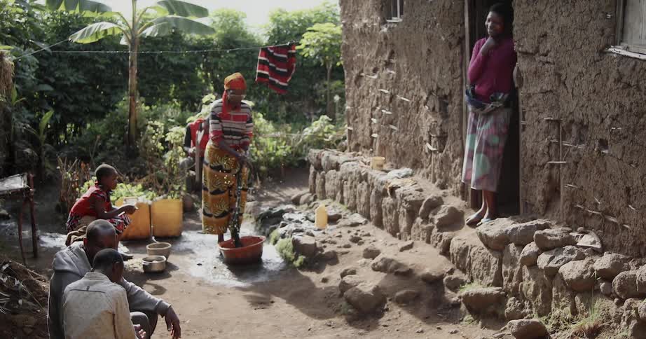 Several adults and children outside doing a washing