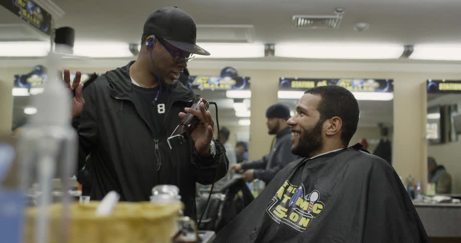 A barber talks to a customer in a barbershop