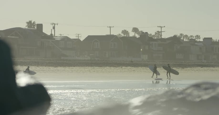Surfers are carrying their surfboards along the beach