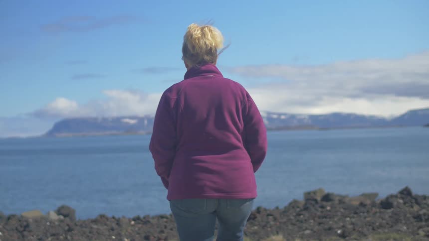 Woman walking on a hill towards water?
