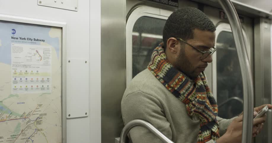 Man looks at phone while riding on subway