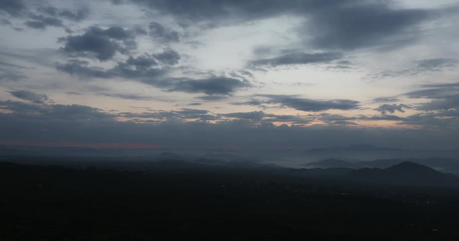 The clouds are dark above the mountain as the sun sets