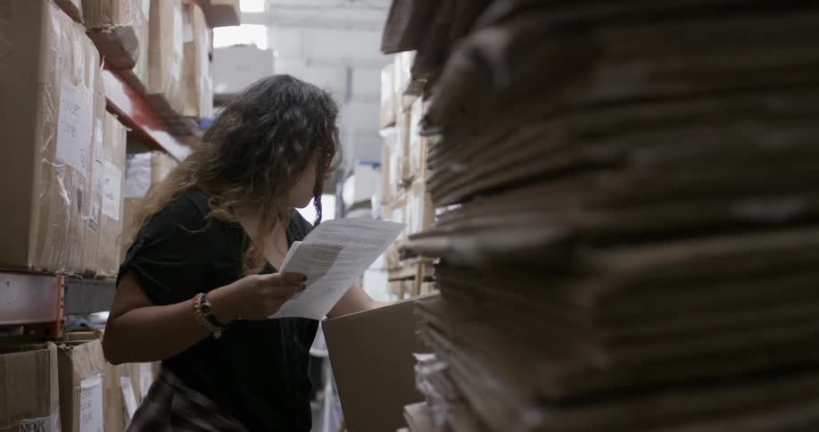 A woman looks through papers in a warehouse