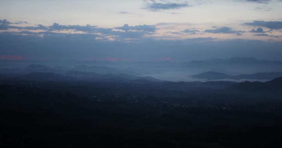 Clouds float over a mountain valley at sunset