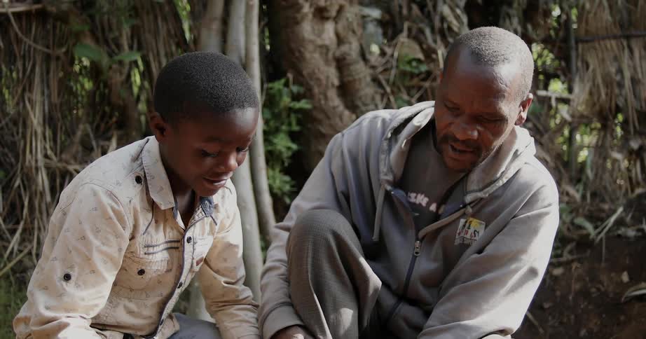 A man and boy sit outside and work together