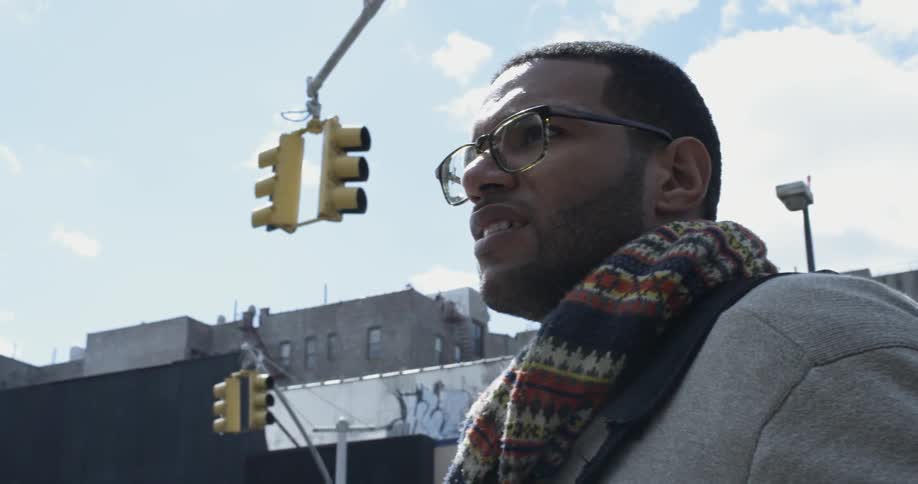 A man with a scarf is at a busy streets intersection