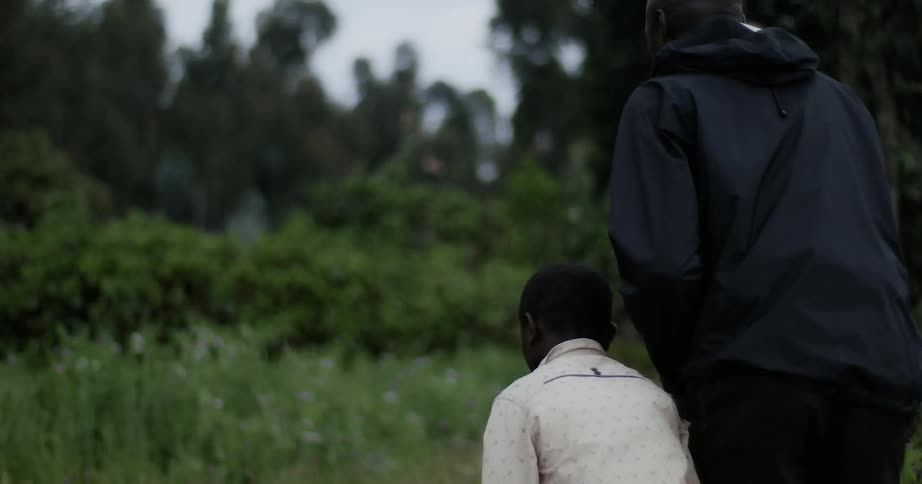 A man and boy walk in a forested area