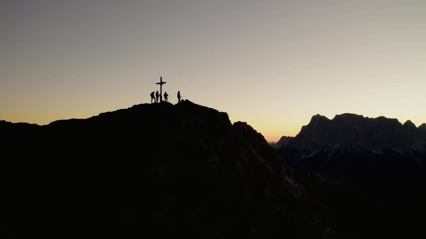 Skiers stand on a peak where a cross has been raised