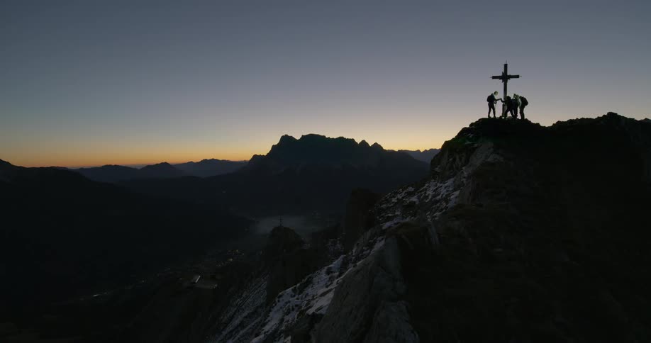 Climbers stand on a peak where a cross has been raised