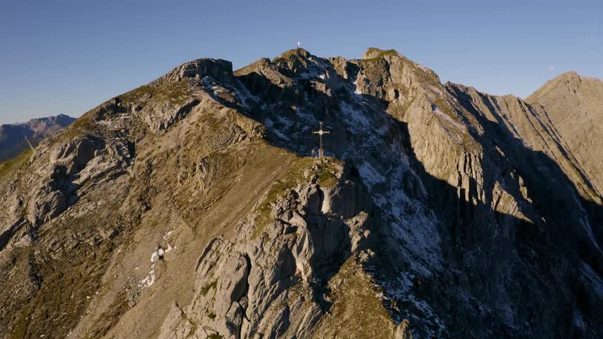 Climbers stand on a peak where a cross has been raised