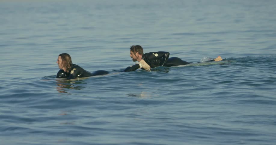 Two people float on their surfboards in the coast