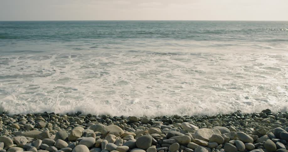 An ocean waves is rolling onto a rocky shore during the day