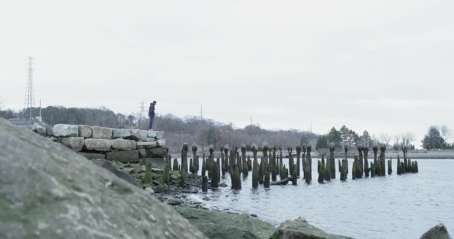 A man stands next to a lake