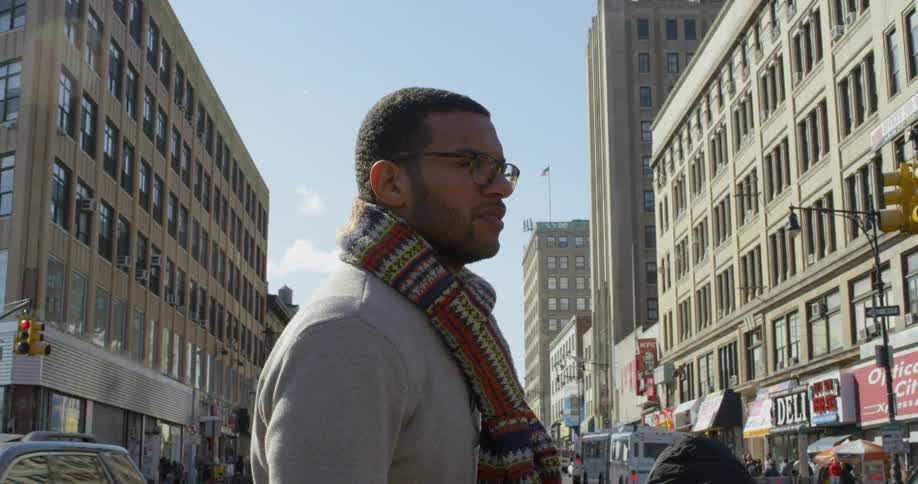A man in a scarf is standing on a very busy street